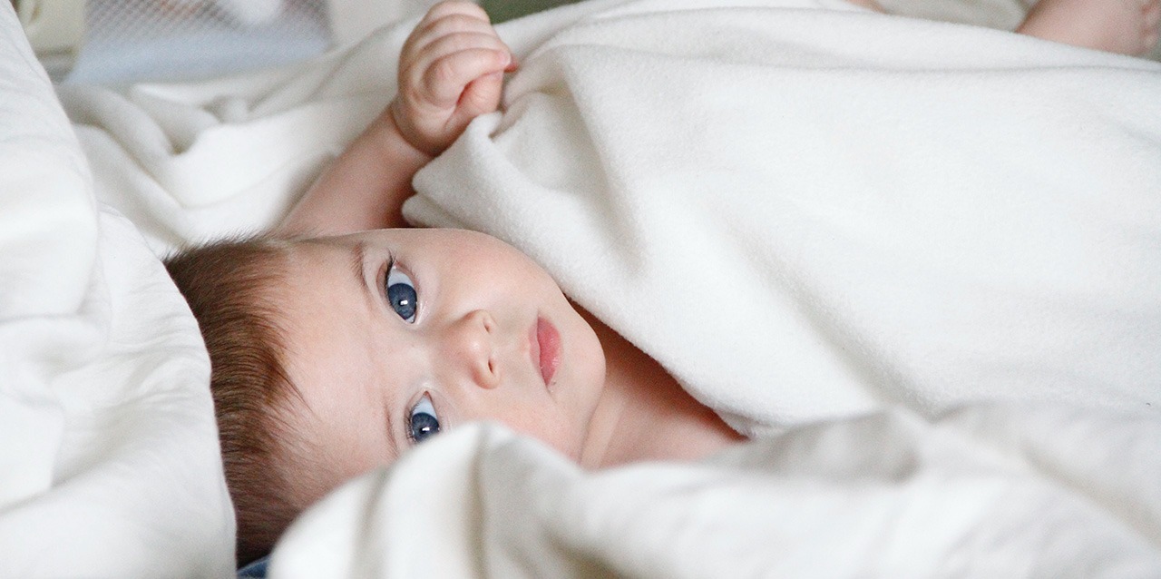 Bébé aux yeux bleus allongé sur un matelas